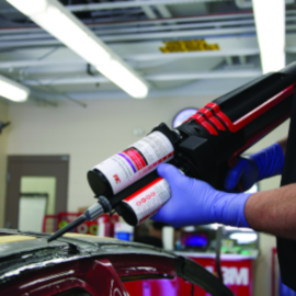 3M body shop technician using panel bonding adhesive on red car with applicator