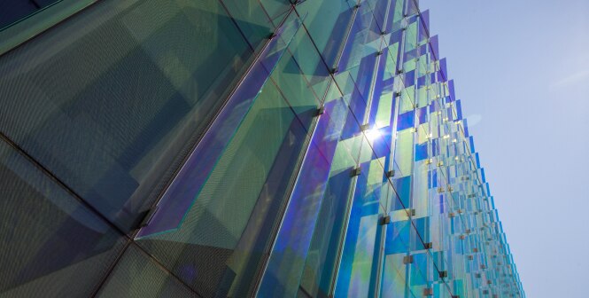 A close-up view of a modern building facade with a series of glass panels.
