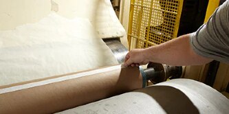 Image of a worker placing tape on a core to begin winding a roll of paper
