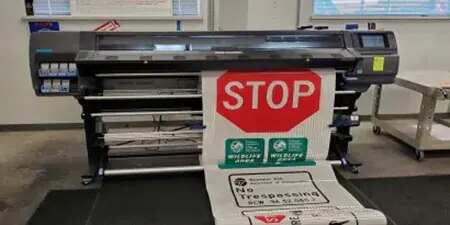 A red 'stop' sign for road traffic being printed from a commercial digital printer.
