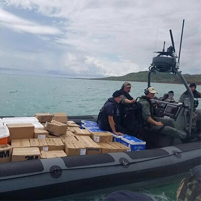 Several people in a supply boat bringing boxes of products
