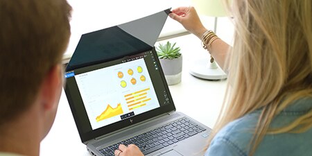 Woman flipping up a laptop 3M™ COMPLY™ Privacy Filter Attach Solutions on her laptop, showing a coworker her screen contents without the filter
