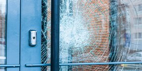 Close up photo of glass door with large cracked impact
