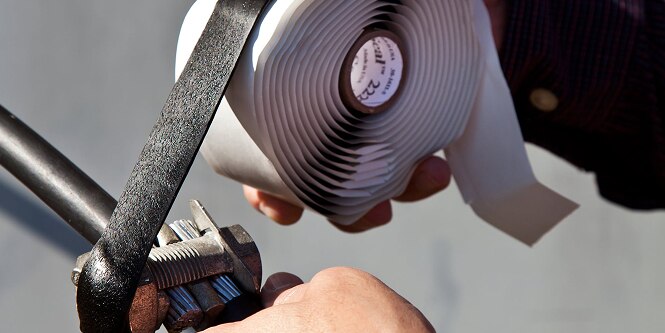 worker adding electrical padding to bolted cable
