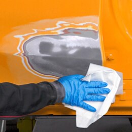 Hand wiping car panel with paper towel.