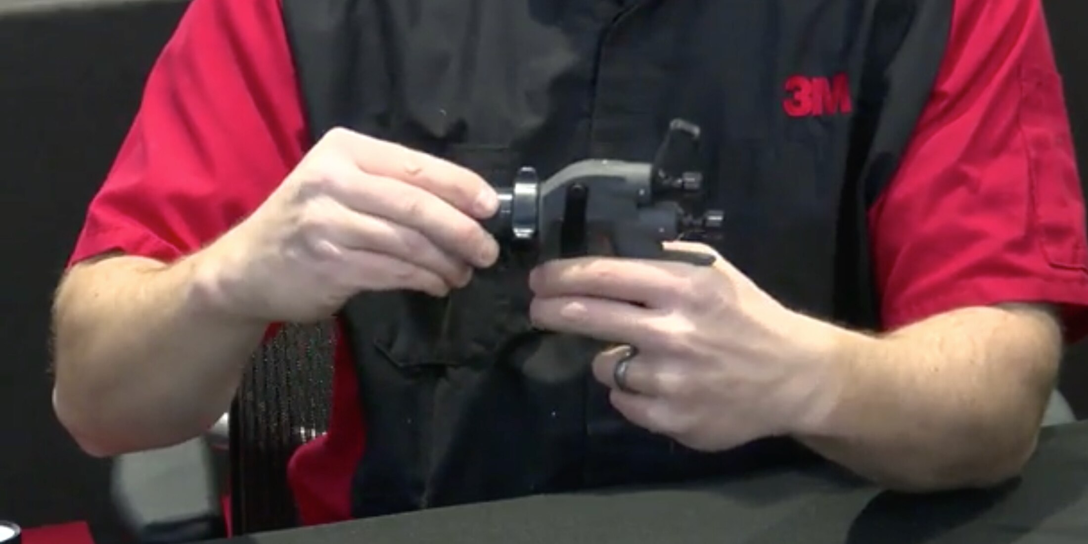 Video screen capture of a man holding a paint spray gun and demonstrating how to use it properly. 
