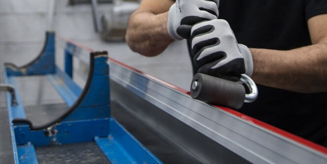 Gloved hands rolling tape onto a piece of metal 
