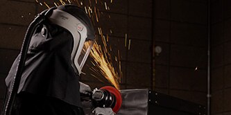 Worker wearing a PAPR and finishing steel.
