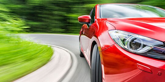 red car driving around a curve - automotive 3M Academy
