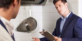 Inspector talking to chef in commercial kitchen
