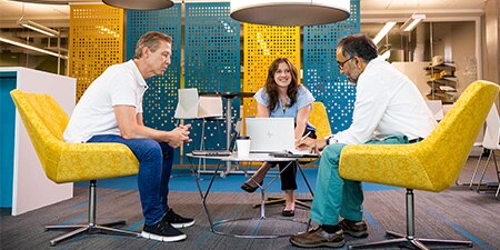Three people sitting in chairs in an office.
