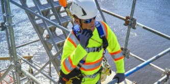 worker on scaffolding speaking through protective comms equipment
