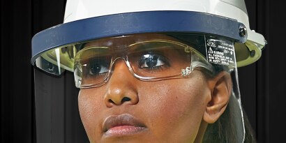 worker wearing safety glasses and a faceshield attached to hard hat

