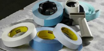 Image of various rolls of splicing tapes and a tape gun
