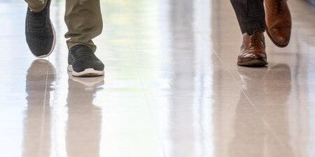 close up of shoes walking on a resilient floor that is clean and reflective
