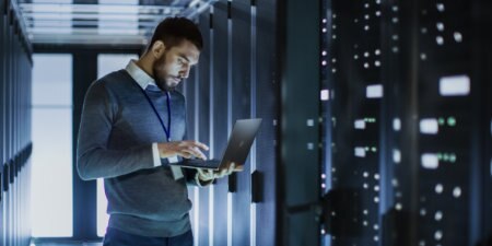 technician on laptop in front of servers
