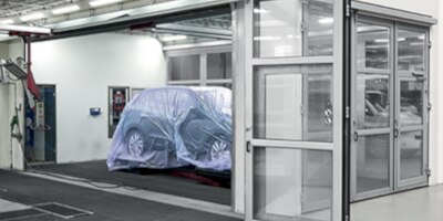 Vehicle wrapped in plastic sheeting in paint booth.