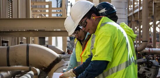Workers in PPE safety gear reviewing site safety plans.
