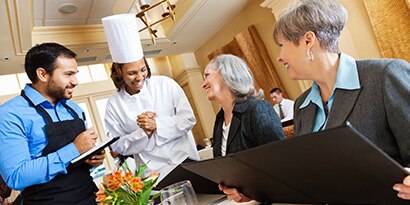 Chef talking to customers at restaurant
