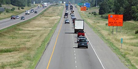 A highway work zone with traffic passing by orange road
