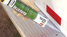 Image of a gloved hand applying 3M™ Adhesive Sealant 740 UV between a running board and a vehicle