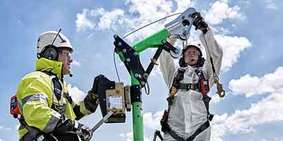 Workers in protective gear using a confined space entry davit.
