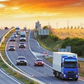 Vehicles driving on a highway at sunset.