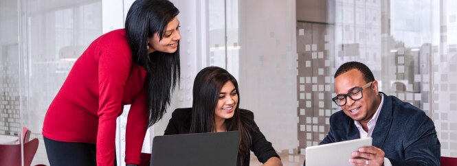 Three colleagues are collaborating in a modern office environment.
