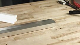 Video still showing a metal bar with 3M™ VHB™ Tape applied and the liner removed, a hand applicator, scissors and a tape roll