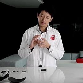 Man in a lab coat holding a manufactured component.