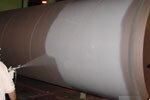 Worker spraying liquid coating on pipe