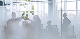 A shot of a meeting happening inside of a frosted-glass conference room
