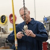 Worker in factory using calipers to measure a piece of equipment on a chain