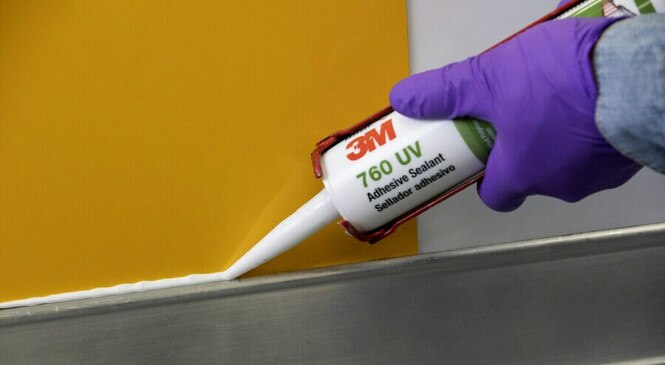 A worker applies adhesive sealant to a horizontal joint
