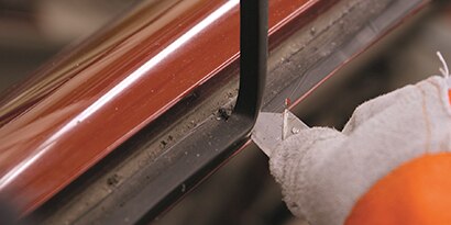 cutting old seam sealer to prepare window opening for new glass
