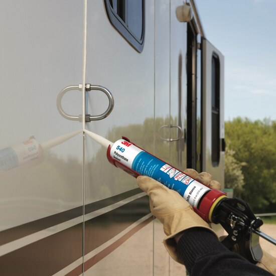 Person applying a 3M™ industrial sealant with a caulking gun to the exterior of a motorhome.
