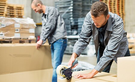 men taping shipping boxes in warehous
