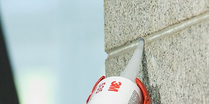 Sealant being applied to seams of concrete wall exterior
