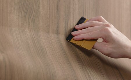 Closeup of squeegee tool being used to install wood pattern film
