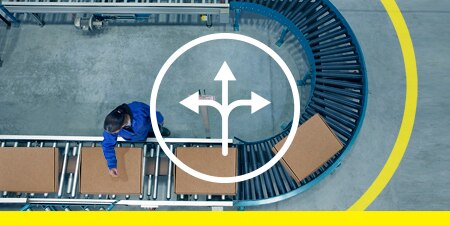 Top-down image of tape marking space around a U-bend conveyor with boxes; overlay of an icon representing flexibility
