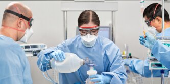 Three healthcare professionals providing patient care with 3M healthcare PPE
