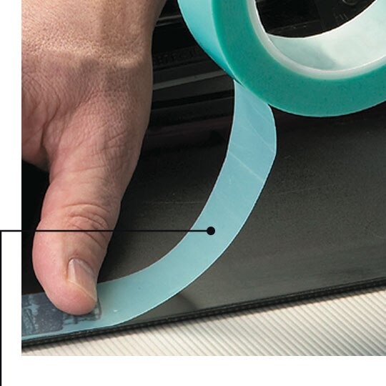 Image of a worker applying non-silicone masking tape to a part