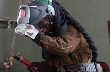 Welder lifting the mask of his 3M™ Adflo™ Powered Air Purifying Respirator (PAPR) System to check his work
