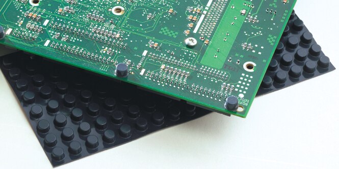 Close-up of a circuit board on top of a sheet of bumpon rubber pads
