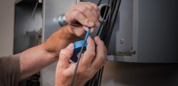 A video still of hands taping a wire.
