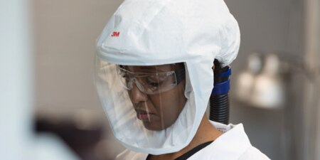 A woman wearing a 3M™ Versaflo™ S-Series headtop.
