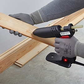 Hot melt adhesive is applied to a piece of wood