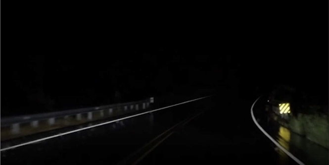 Dark night road with retroreflective sign.
