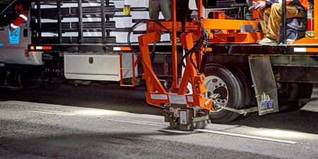 Pavement marking tape being installed on a roadway
