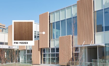 Exterior of building with glass and wood façade featuring product callout of Walnut DINOC Exterior film.
